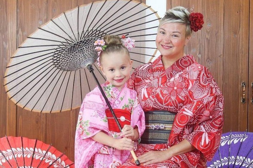 A person in a red kimono with a child in a pink kimono holding a fan. 2