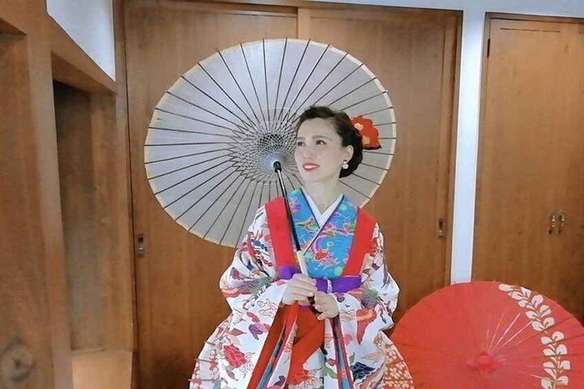 En person klädd i traditionell japansk dräkt som håller i en fläkt. 4
