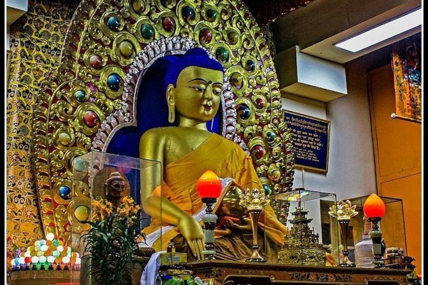 A large golden statue of a seated figure, surrounded by ornate decorations and a blue backdrop. 1