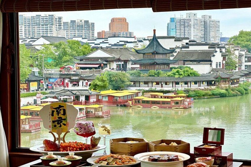 A traditional Chinese riverside view with a table of food and a sign with Chinese characters. 4