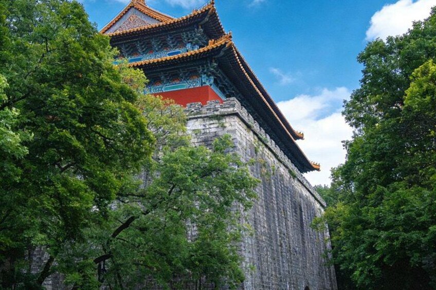 A traditional Chinese building with a tiled roof and stone walls, surrounded by lush green trees. 5