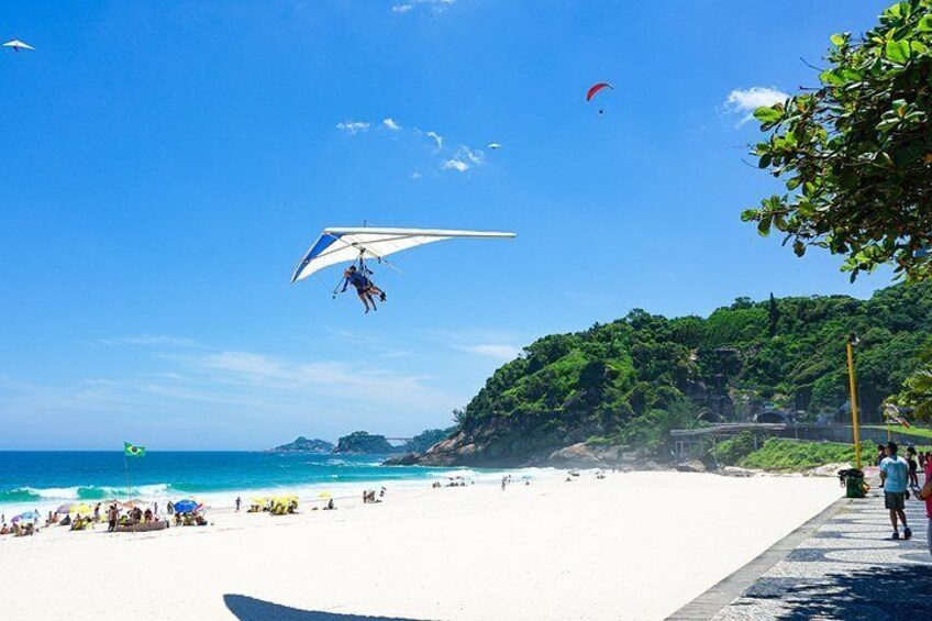 A beach with a paraglider, a clear sky, and a distant coastline. 2
