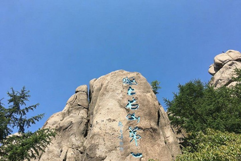 A large rock formation with carved text. 2