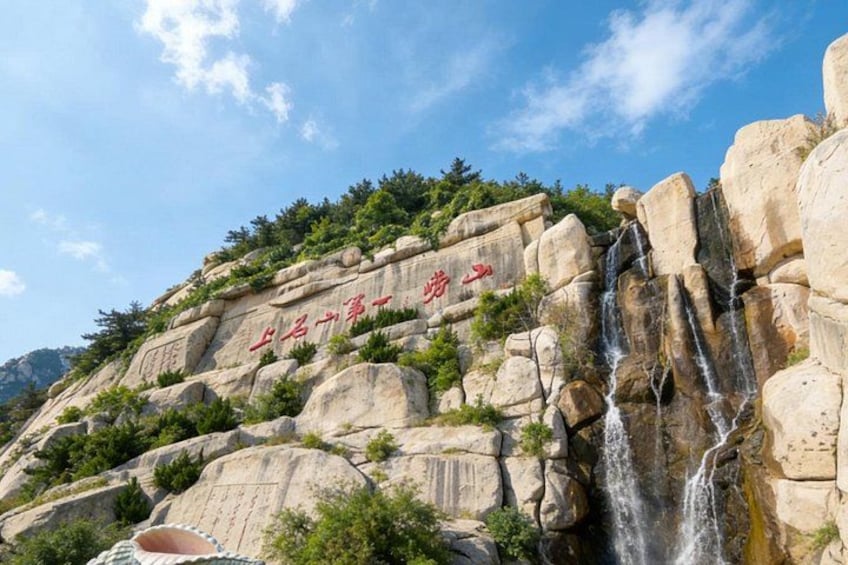 A rocky landscape with a waterfall and Chinese characters on the rock face. 5