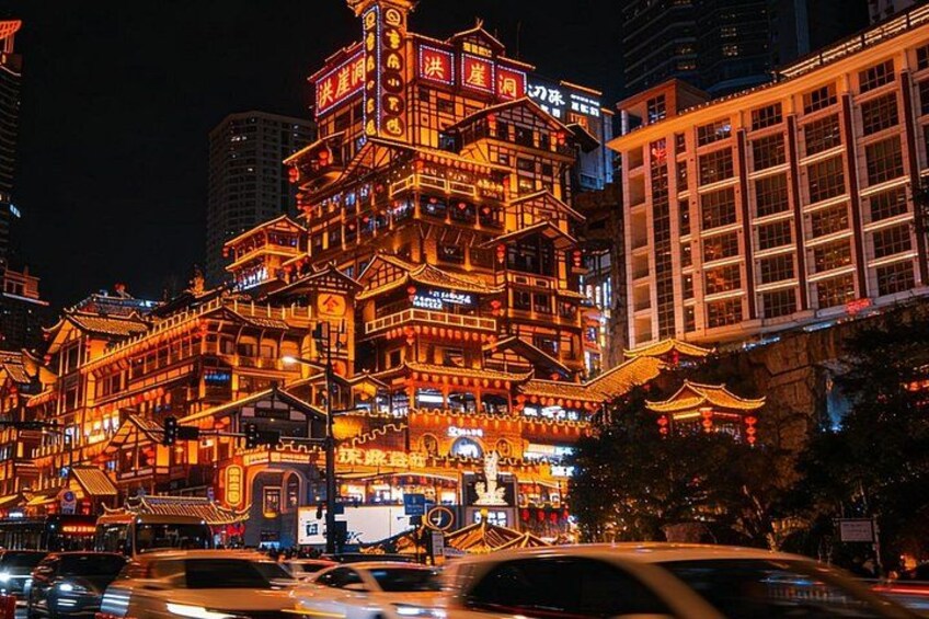 Un bâtiment traditionnel aux couleurs vives, doté de plusieurs étages et orné de détails architecturaux complexes, entouré de bâtiments modernes et bordé de rues animées la nuit. 4