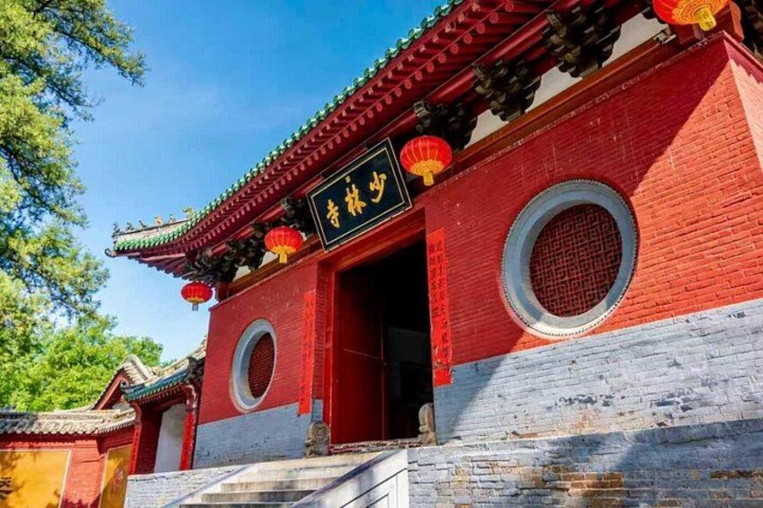 A traditional red and white building with a sign, circular windows, and a tiled roof. 2