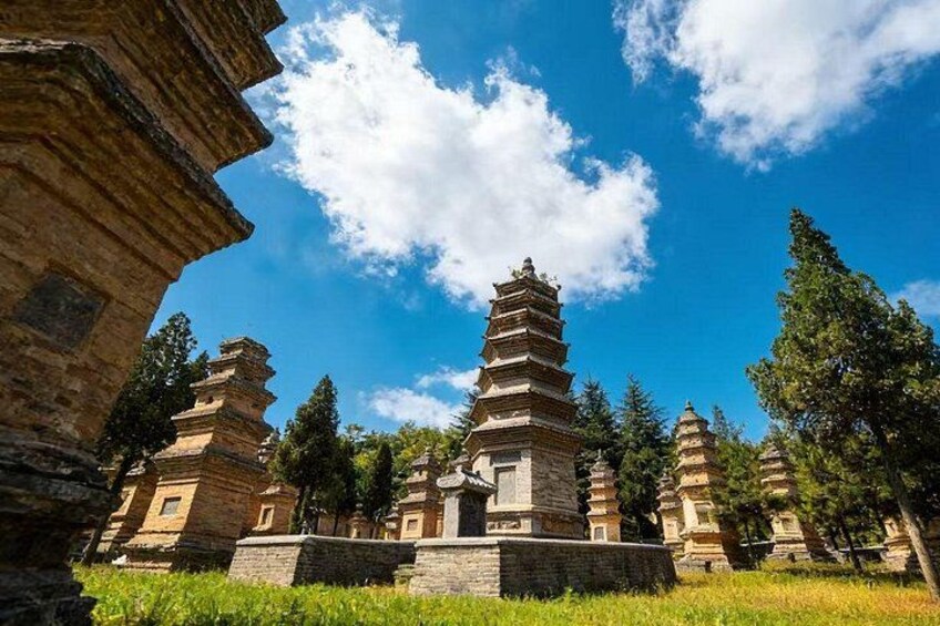 A pagoda-style structure with multiple tiers, surrounded by trees and greenery under a clear blue sky. 3