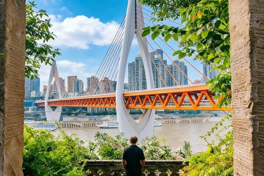 A person standing by a river with a bridge in the background. 1