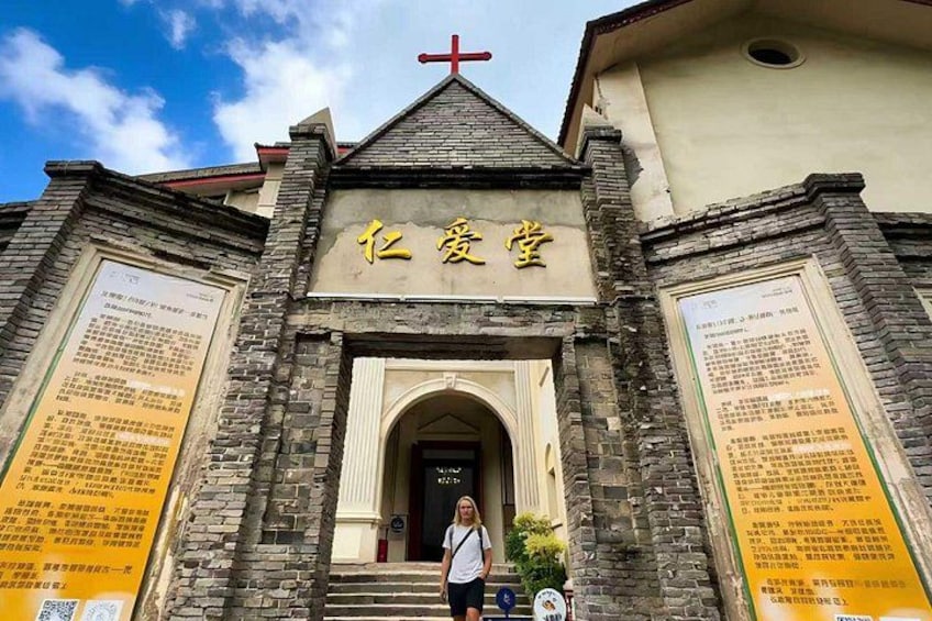 A church with a cross on top, a sign with Chinese characters, and two informational boards on either side. 3