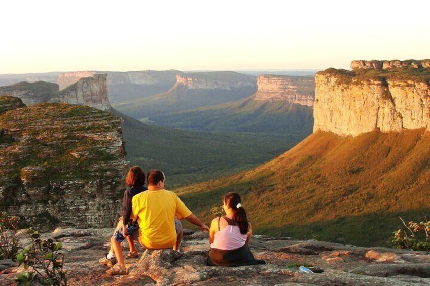 A family of four sitting on a rocky outcrop overlooking a canyon with steep cliffs. 1