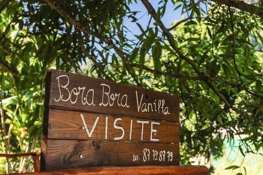 Un letrero de madera con la inscripción 'Bora Bora Vanilla VISITE' y un número de teléfono. 4