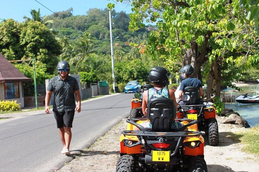Un hombre caminando por una carretera, dos vehículos todo terreno estacionados al lado, y un cuerpo de agua al fondo. 5