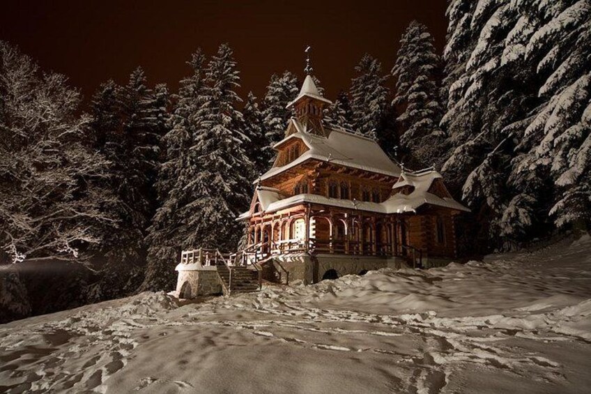 Un edificio cubierto de nieve con un techo tradicional, rodeado de árboles cargados de nieve. 3