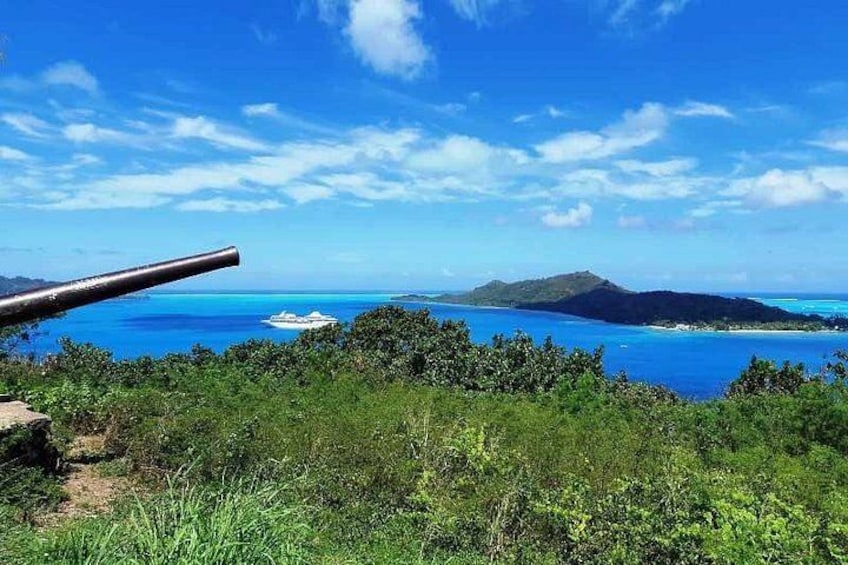Paesaggio costiero con un cannone, vegetazione lussureggiante e un mare blu limpido. 2