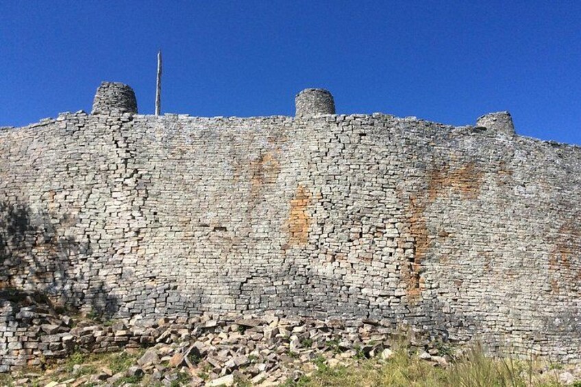 A stone wall with a flagpole and two cylindrical structures on top. 1