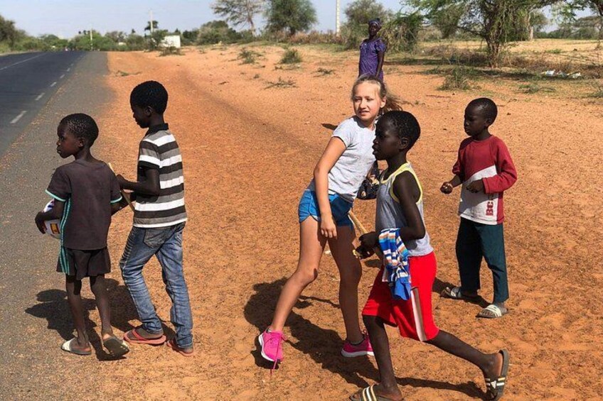 Children playing near a road in a rural setting with sparse vegetation and a clear sky. 5