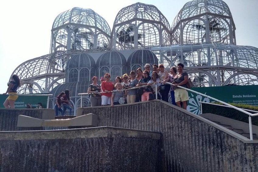 Un grupo de personas de pie en una escalera con un jardín botánico y grandes estructuras de vidrio al fondo. 2