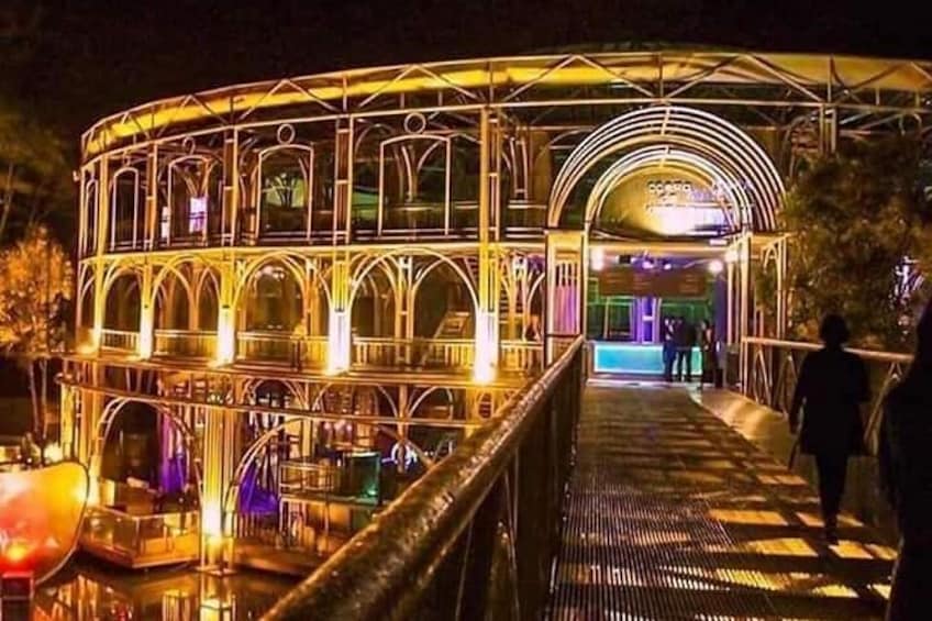 Un puente luminoso y ricamente decorado con arcos y barandales, que conduce a un edificio con un letrero. 1