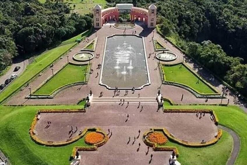 Una gran fuente rectangular rodeada de jardines cuidados y un edificio central con una torre de reloj. 4