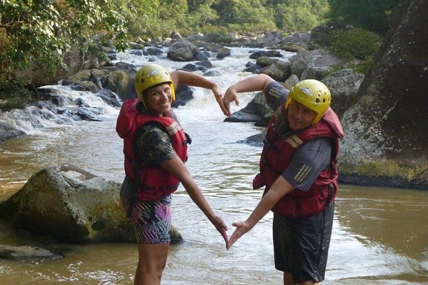Two people in life jackets and helmets by a flowing river. 3