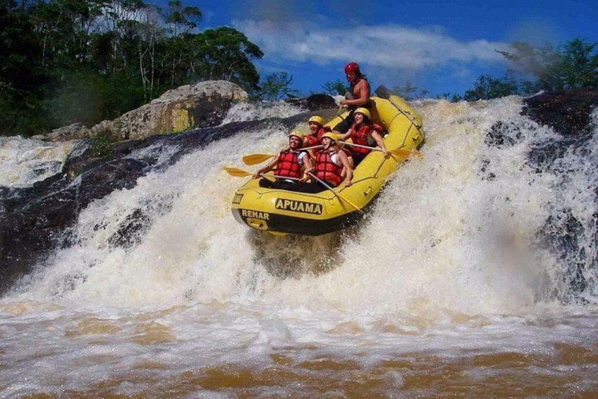 A yellow raft with people wearing life jackets navigating through a turbulent river. 1