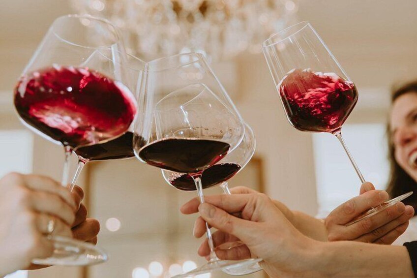 Three people holding wine glasses filled with red wine, toasting. 2