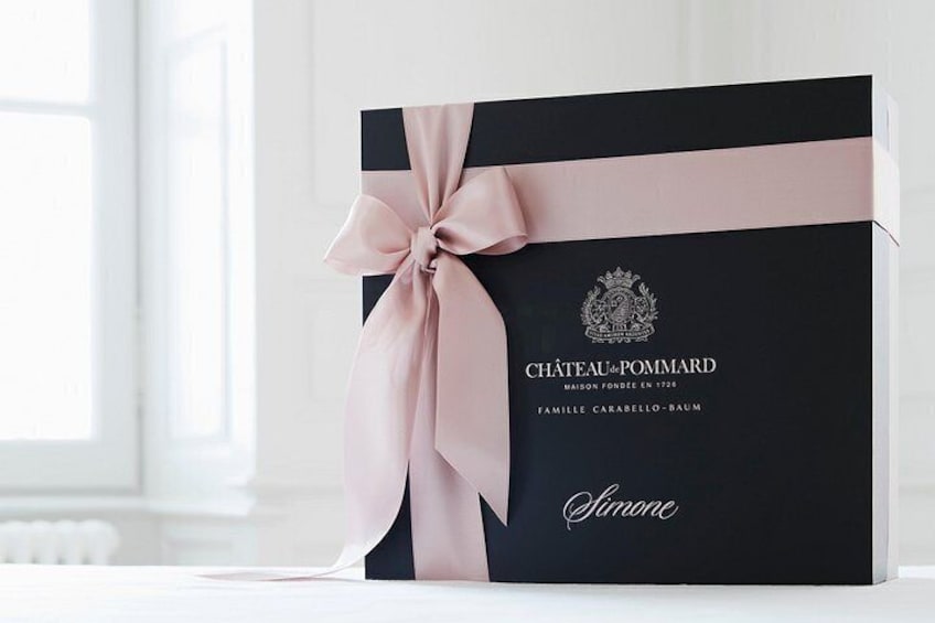 A black gift box with a pink ribbon and the text 'CHÂTEAU-POMMARD' and 'FAMILLE CARABÉLLO-BAUM' on it. 4