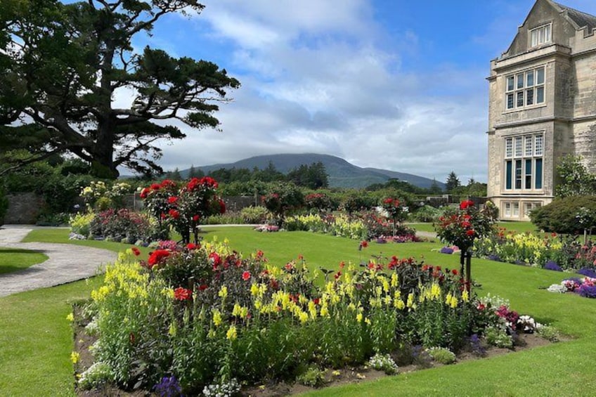 A landscaped garden with a variety of colorful flowers, a large tree, and a building in the background. 5