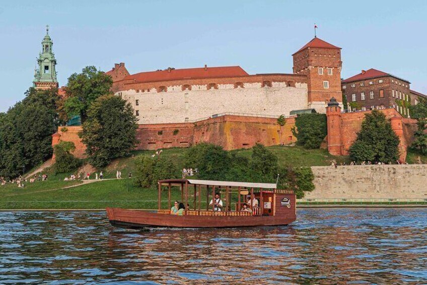 A wooden gondola against the backdrop of Wawel, illuminated by the setting sun.