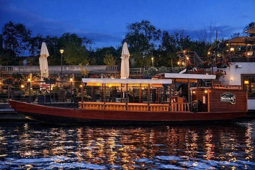 En båt låg förtöjd vid en restaurang vid vattnet, som hade uteservering och parasoller. 5