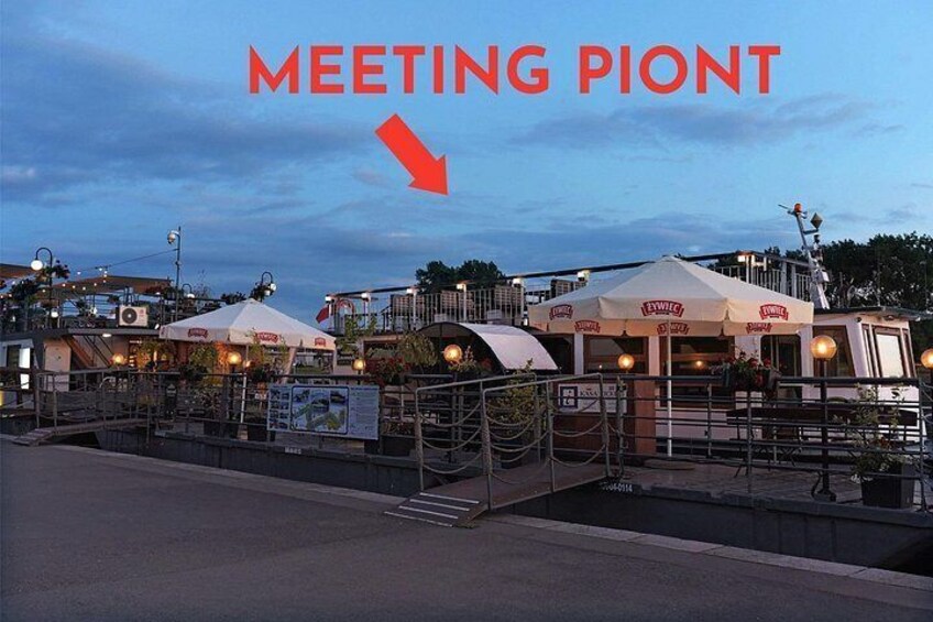 Ett område vid vattnet med en restaurang, tält och en båt som ligger förtöjd i närheten. 2