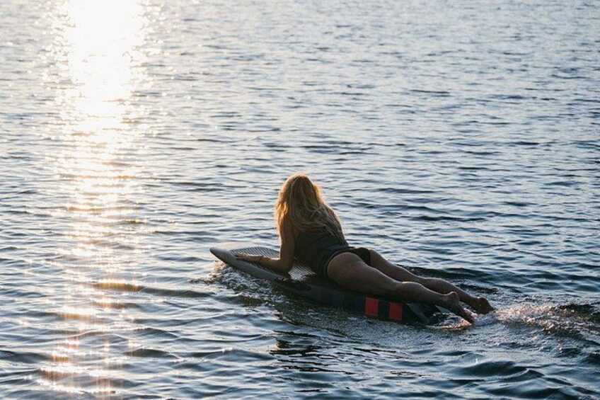 Una persona sentada en una tabla de surf en aguas tranquilas durante el atardecer. 2