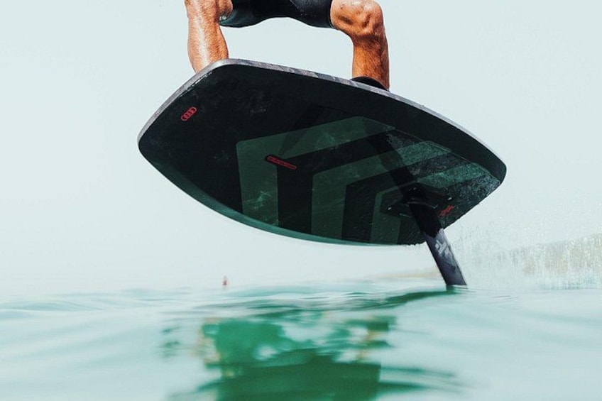 Una persona montando una tabla de surf negra con un logotipo distintivo en la parte inferior. 5