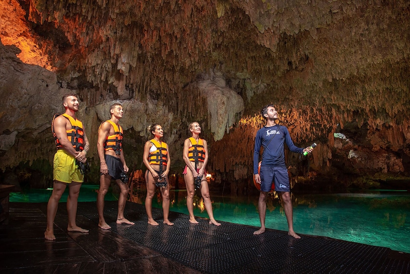 Un groupe de personnes se trouve dans un endroit qui ressemble à une grotte, avec une piscine. 1