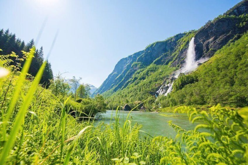A river flowing through a lush valley with a waterfall and dense greenery. 3
