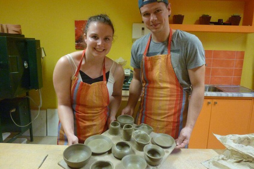 Two people in aprons standing in a kitchen with bowls and plates on the counter. 2