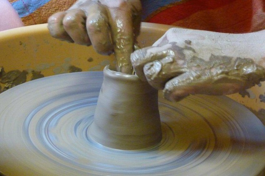 Hands shaping a clay pot on a spinning wheel. 3