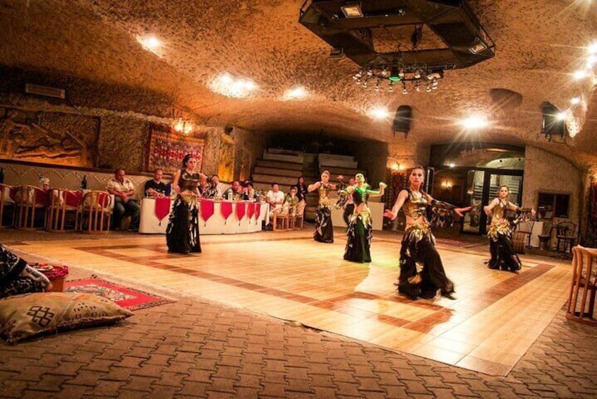 Un groupe interprétant une danse traditionnelle dans un lieu rustique aux murs de pierre et au plancher en bois. 4