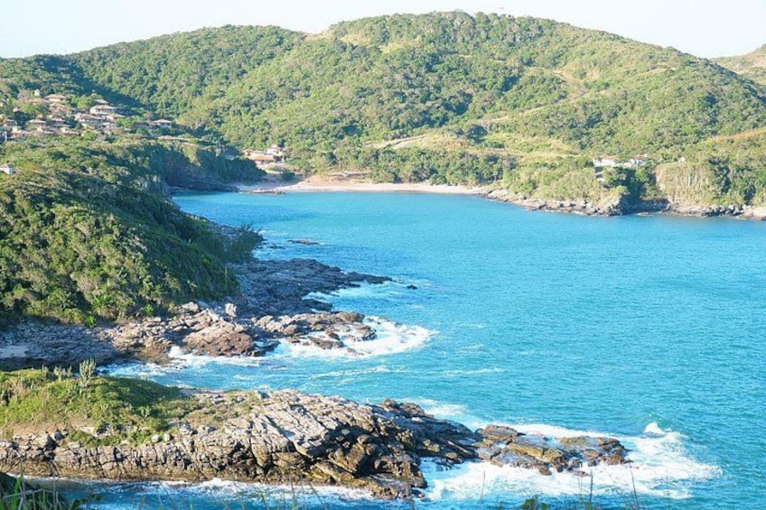 Un paisaje costero con costas rocosas, mar azul cristalino y colinas verdes. 3