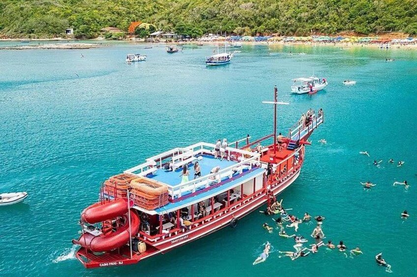 Un barco rojo grande con pasajeros, rodeado de aguas turquesas cristalinas y varios botes más pequeños. 1