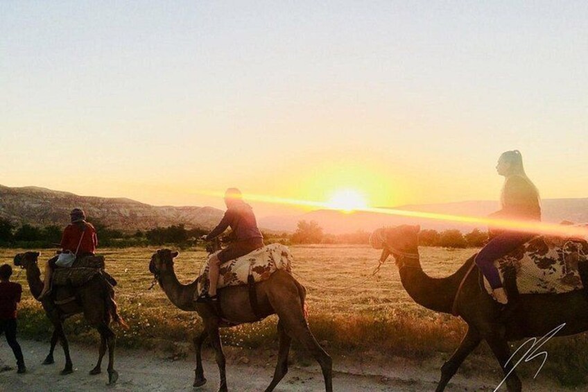 A sunset with camels and riders in a desert landscape. 5