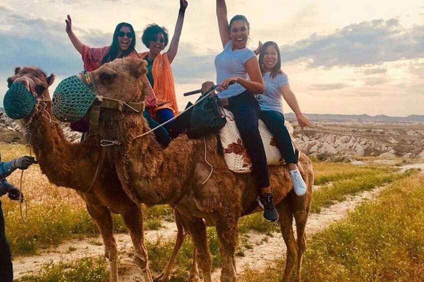A camel with people riding it on a dirt path. 3