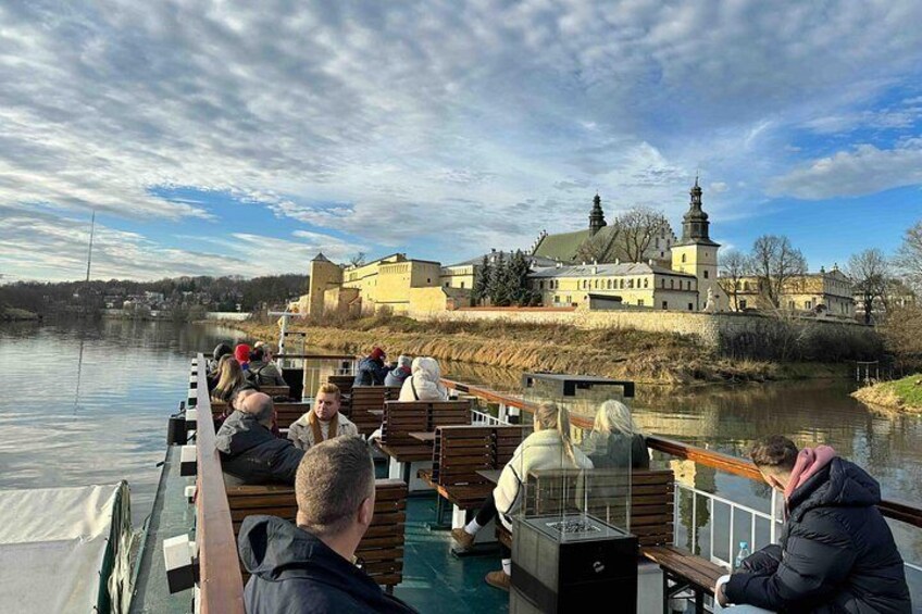 A boat tour with passengers enjoying the view of a historic castle by the river. 5