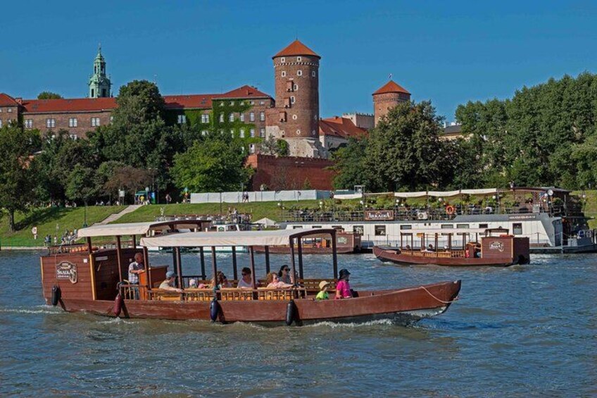 A riverboat tour with passengers, a historic building, and a tower in the background. 4