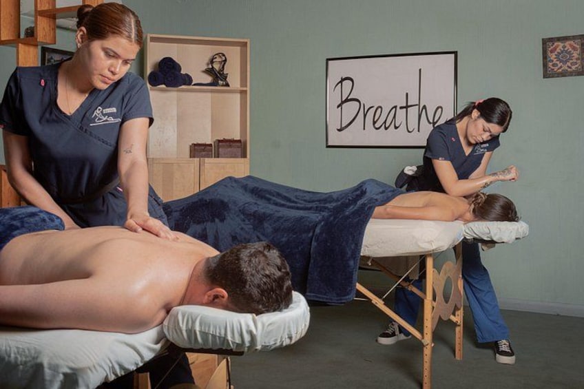 A massage therapy session in a room with a 'Breathe' sign on the wall. 5