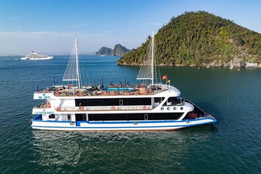 Un bateau blanc et bleu, baptisé « La Castada Daily », à deux mâts, naviguait sur des eaux calmes, près d’une île boisée. 1