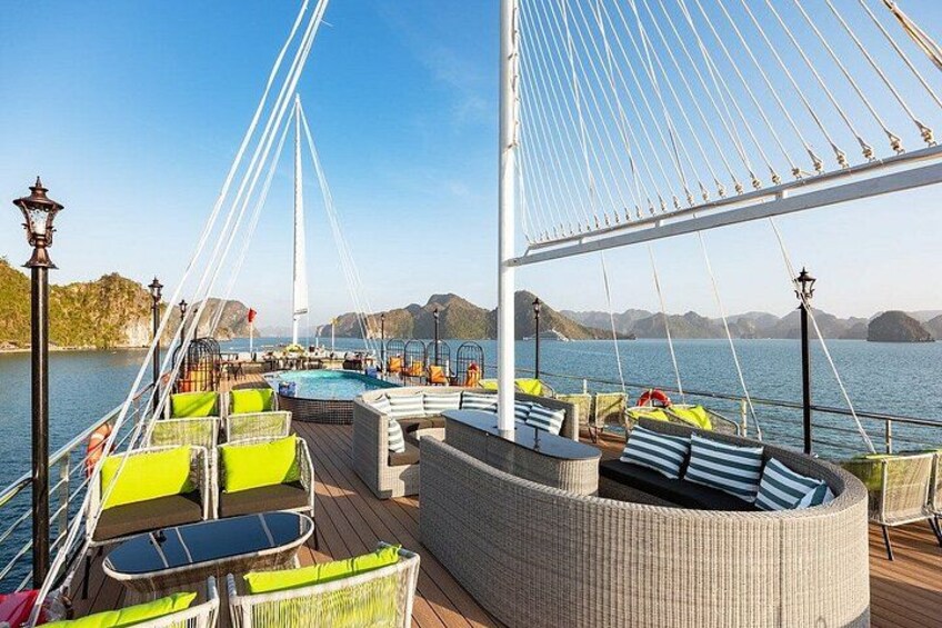 Une terrasse avec coin salon extérieur, une piscine et une structure en forme de pont. 2