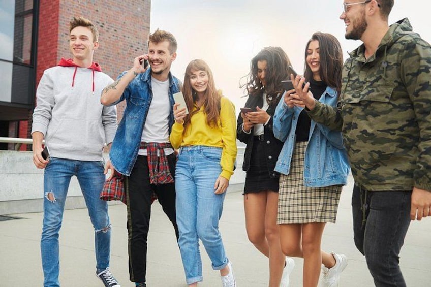 A group of people standing on a rooftop, some holding phones. 5