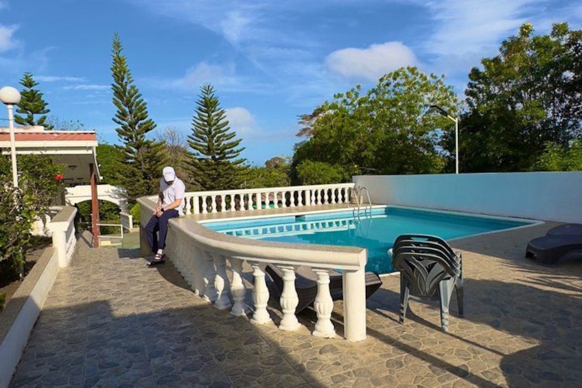 A man sitting by a pool, surrounded by stone steps and a white railing. 5