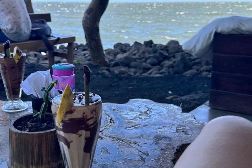 A table with drinks and a view of the ocean. 3